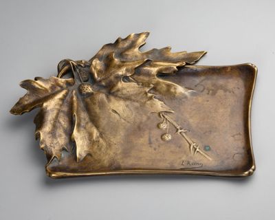 brass plate with leaves and flowers on it on a gray surface