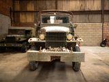 a old military truck parked in a garage with other military vehicles in the background