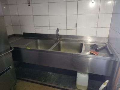 deux éviers dans une cuisine, avec un réfrigérateur en arrière-plan