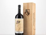 La bouteille de vin se trouve à côté d'une caisse en bois sur laquelle est dessiné un motif.