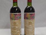 two bottles of wine sitting on top of a table next to each other