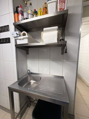 a kitchen with a sink and a trash can in it