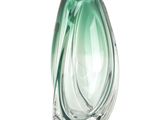 un vase en verre vert posé sur une surface blanche