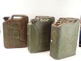 trois jerrycans verts posés les uns à côté des autres sur une surface blanche