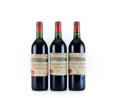 trois bouteilles de vin rouge posées l'une à côté de l'autre sur une surface blanche