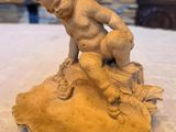 a statue of a boy sitting on a shell on a table