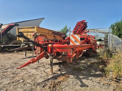 un semi-remorque rouge garé sur un terrain en terre battue à côté d'un bâtiment