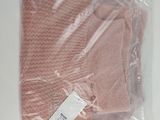 pink knitted hat in a plastic bag on a white surface