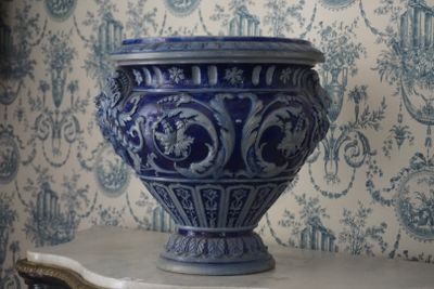 un vase bleu posé sur une table devant un papier peint