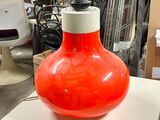 a red vase sitting on top of a white table