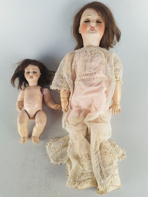 two old dolls sitting next to each other on a table