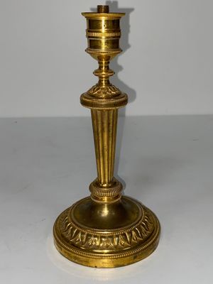 une bougie dorée posée sur une table blanche