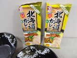 two packages of ramen sitting next to a bowl of ramen