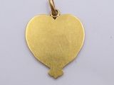 a close up of a gold heart shaped pendant on a white surface