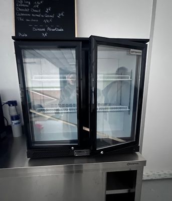 stainless steel counter top with two glass doors and a chalk board on the wall