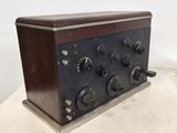 une vieille radio posée sur une table en bois, près d'un mur blanc