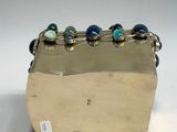 a silver box with blue and green glass beads on it