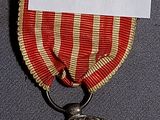 a silver medal with a red ribbon around it