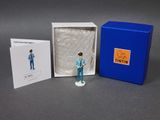 une petite figurine représentant un homme en costume bleu, dans une boîte bleue