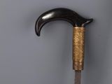 a close up of a cane with a wooden handle on a gray surface