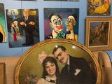 une photo représentant un homme et une femme assis sur une chaise devant un tableau représentant des clowns accroché au mur