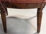 an old wooden chair with a red upholstered seat on a white floor