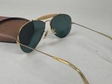 sunglasses with gold frames and green lenses are laying on a white surface