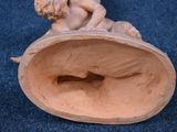 a figurine of a boy sitting on top of a bowl