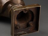 bronze sculpture of a hand holding a pipe with a hole in the middle