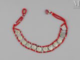 un gros plan sur un bracelet en ficelle rouge orné de pièces de monnaie