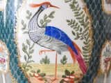 a vase with a bird painted on it sitting on a table