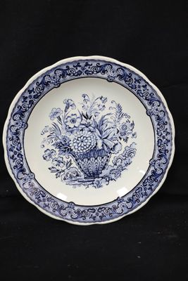 a blue and white plate with a basket of flowers on it