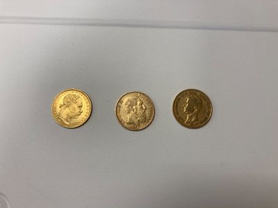 trois types différents de pièces d'or sur une surface blanche
