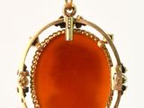 an image of a gold pendant with an orange stone in the center