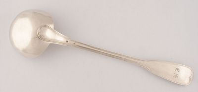 une cuillère en argent ancienne et son repose-cuillère posés sur une surface blanche