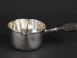 a silver saucepan with a wooden handle on a black background