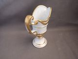 a white vase with a gold decoration on it