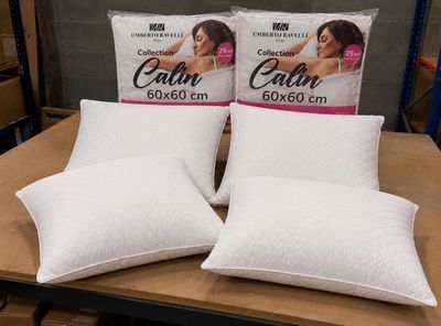 trois oreillers posés sur une table dans un magasin où se trouvent des cartons d'oreillers
