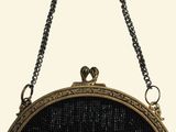 the black beaded purse is hanging from a chain