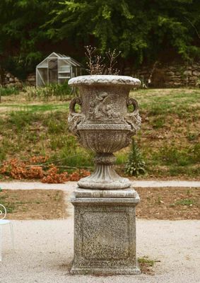 deux vases posés sur un socle au milieu d'un parc