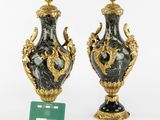 two black and gold vases with a green card in front of them
