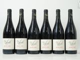 six bouteilles de vin sont alignées sur une table