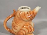 a small orange and white cat shaped teapot on a table