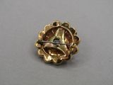 a close up of a gold brooch with a pin in the middle