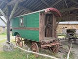 un chariot couvert vert et rouge garé dans l'herbe