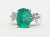 gros plan d'une bague avec une pierre verte entourée de diamants
