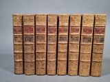 six vieux livres sont alignés sur une surface grise