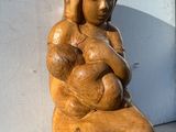 une statue représentant une femme tenant un bébé sur un rebord