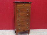 a small wooden chest of drawers in front of a red wall