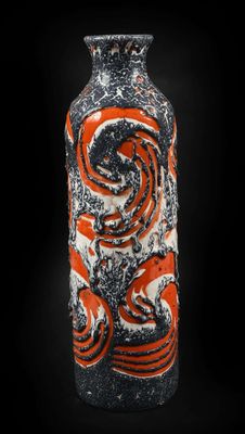 un vase orange et noir posé sur une surface noire
